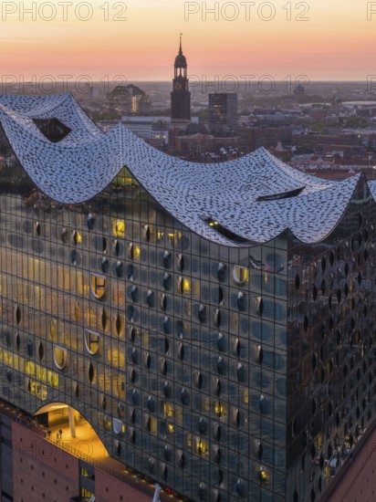 Aerial view of the Elbphilharmonie at sunset with illuminated windows and view over Hamburg and the main church St Michaelis (Michel), Hamburg, Germany