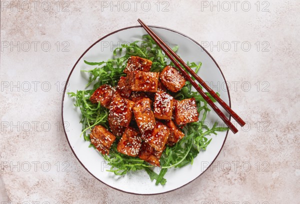 Fried salmon slices, teriyaki with sesame seeds, with arugula salad, top view