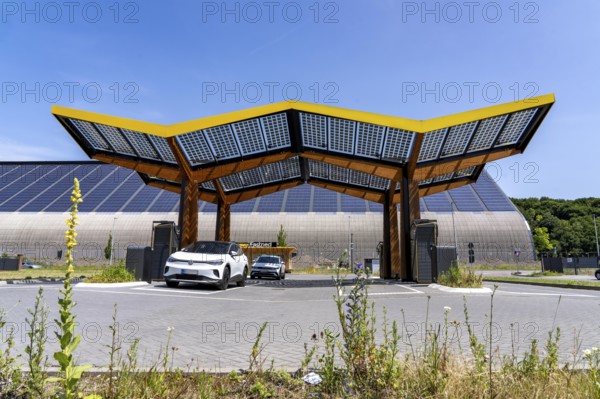 Electric charging station on the site of the former Lohberg colliery in Dinslaken, operated by Fastned, uses electricity from wind power and solar energy, fast-charging columns, with its own solar roof, in the background the 11, 500 square metre solar roof on the colliery's former coal mixing hall, North Rhine-Westphalia, Germany