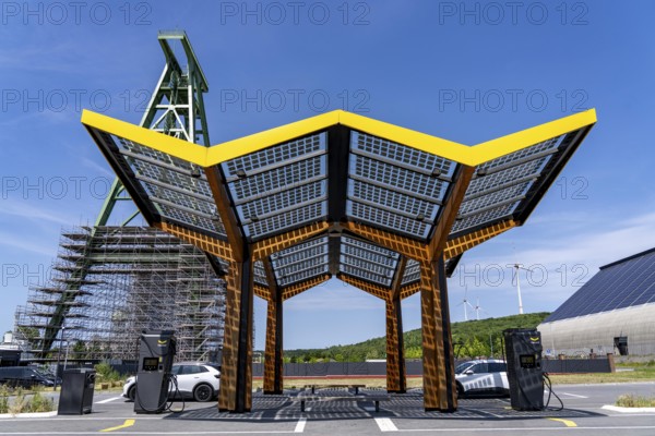 Electric filling station on the site of the former Lohberg colliery in Dinslaken, operated by Fastned, uses electricity from wind power and solar energy, fast-charging columns, with its own solar roof, in the background the 11, 500 square metre solar roof on the colliery's former coal mixing hall, wind farm on the Lohberg slagheap, Lohberg colliery headframe, North Rhine-Westphalia, Germany