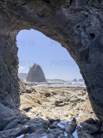 Large rock with a hole and people in the foreground, Hole in The Wall, Rialto Beach, Olympic National Park, Washington, USA, North America