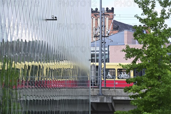 A suburban railway is reflected in the façade of the Futurium in Berlin-Mitte
