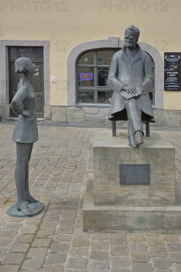 Monument to philosopher Friedrich Nietzsche, bronze sculpture, modern art, standing female figure, girl, sitting on chair, communication, conversation, listening, inscription, Holzmarkt, Saale, Naumburg, Saxony-Anhalt, Germany