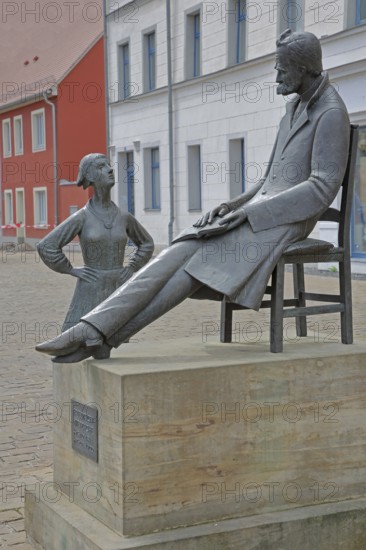 Monument to philosopher Friedrich Nietzsche, bronze sculpture, modern art, standing female figure, girl, sitting on chair, communication, conversation, listening, Holzmarkt, Saale, Naumburg, Saxony-Anhalt, Germany