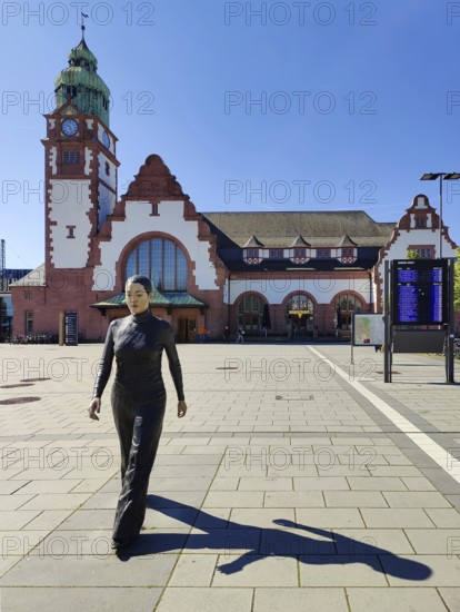 Realistic artwork entitled Walking Woman by Sean Henry on the square in front of the railway station in Bad Homburg vor der Höhe, Hesse, Germany