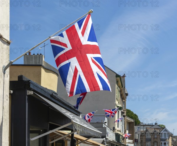 Union Jack flags on shops in street of historic buildings, The Strand, Dawlish, south Devon, England, UK