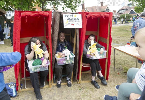 Three women forming human fruit machine game at village summer fete, Bawdsey, Suffolk, England, UK