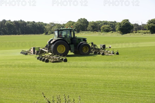 John Deere tractor mowing grass turf field, Butley, Suffolk, England, UK
