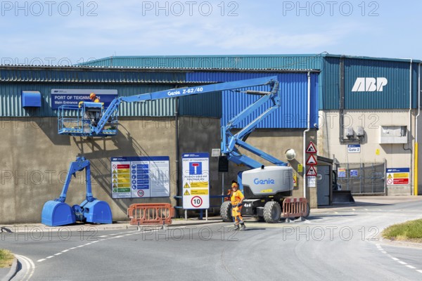 Man on cherry picker machinery cleaning sign, Port of Teignmouth, Teignmouth, south Devon, England, UK