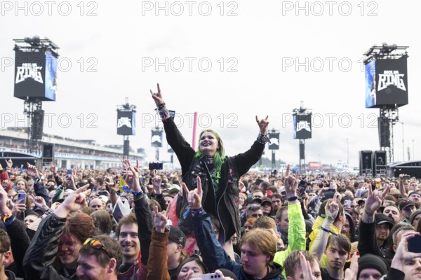 Festival visitor on shoulders with a French fries fork shaped like a hand at the Rock am Ring Festival on Friday, Nürburgring race track race track, 07.06.2025