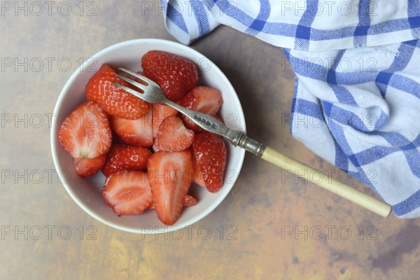 Sliced strawberries in hull with fork, Fragaria