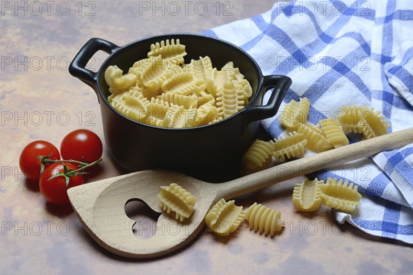 Italian pasta, Radiatori variety, in pots and heart-shaped cooking spoon