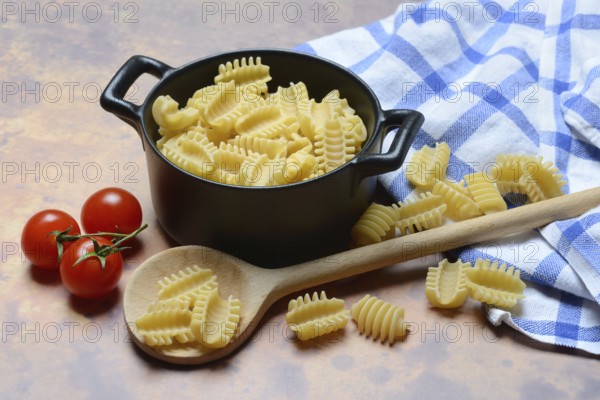 Italian pasta, Radiatori variety, in pots and wooden spoon