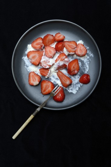 Sliced strawberries and whipped cream on a plate, dessert