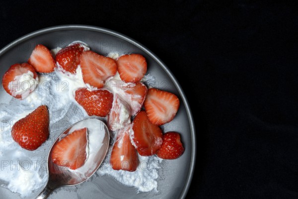 Sliced strawberries and whipped cream on a plate, dessert