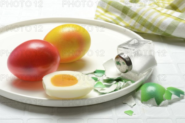 Easter eggs and salt shaker on plate, partially peeled