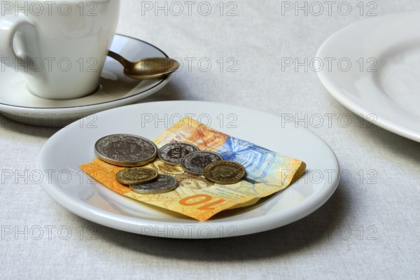 Tip, Swiss coins and Swiss franc note on plate, Switzerland