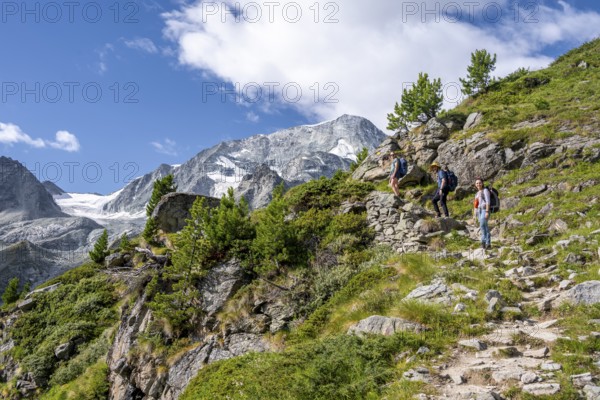 Three mountaineers on a hiking trail, mountain landscape near Arolla, behind mountain peak Mont Collon and glacier Glacier de Tsijore Nouve, Valais, Western Alps, Switzerland