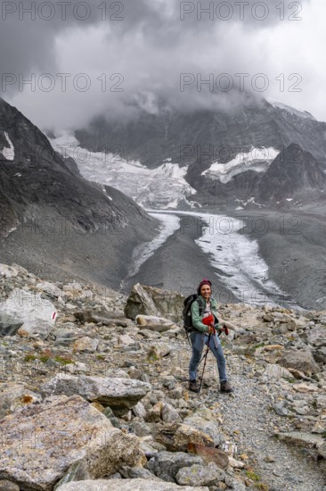 Mountaineer descending Col de Riedmatten, view of glacier Glacier de Cheilon and mountain peak Mont Blanc de Cheilon in clouds, Valais, Western Alps Switzerland