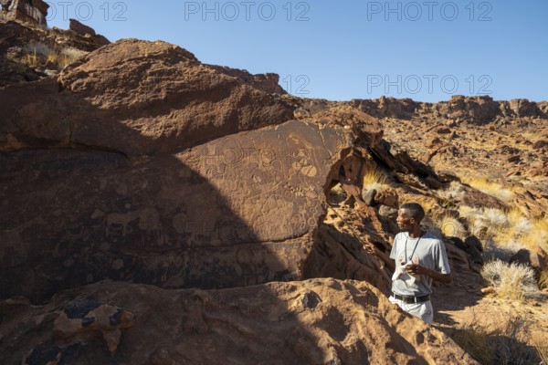 Tourist guide explains the details of the rock engravings at Twyfelfontein, Twyfelfontein, Kunene, Namibia