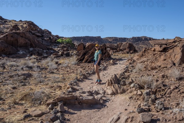 Tourist on a hiking trail in a barren landscape, visiting the rock engravings of Twyfelfontein, Twyfelfontein, Kunene, Namibia