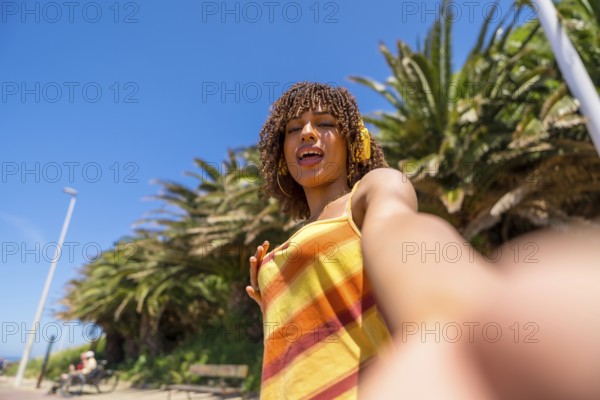 Carefree young woman enjoying summer holidays taking a selfie while listening to music with headphones in a tropical location