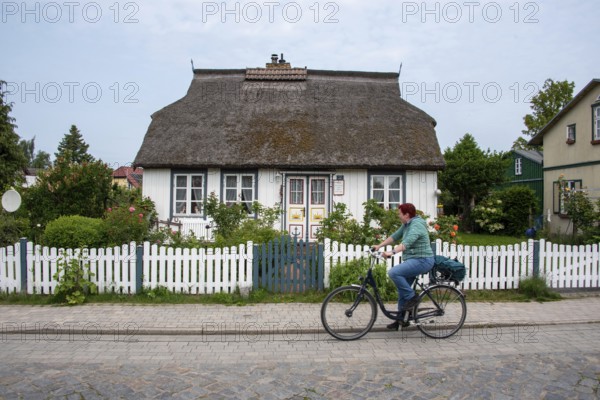 Woman with bicycle in front of a traditional thatched house, Wieck, Mecklenburg-Vorpommern, Germany