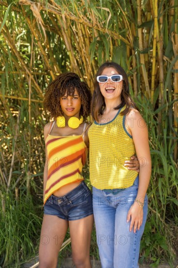Two female friends hugging and smiling in a vibrant bamboo forest, soaking up the sun and enjoying their carefree day together