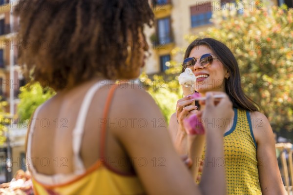 Two friends savoring ice cream cones on a sunny summer day in the city, sharing laughter and creating joyful memories together