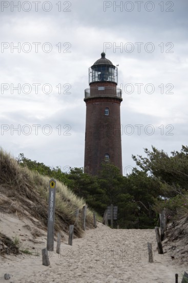 Path through sand dunes leads to the Darßer Ort lighthouse, surrounded by nature and cloudy skies, Prerow, Mecklenburg-Vorpommern, Germany