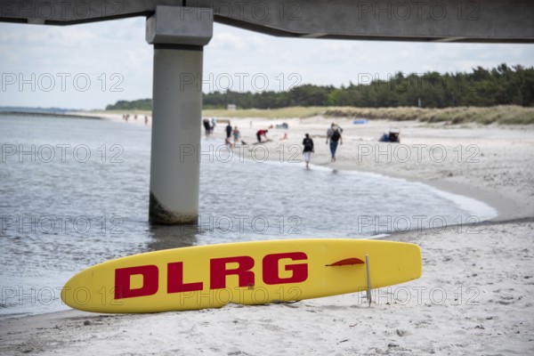 Yellow rescue board with red DLRG print on the beach under the bridge pillar, Prerow, Mecklenburg-Vorpommern, Germany