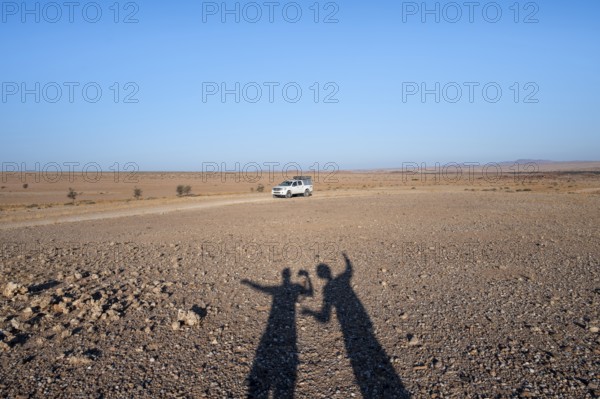 Shadow of two people, holiday, off-road car on a sandy track, Brandberg, Damaraland, Namibia