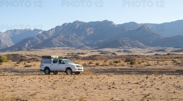 Tourist with off-road car on a sandy track, rock formation, Brandberg, Damaraland, Namibia