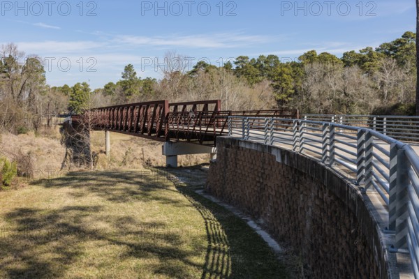 Steel bridge along paved biking and walking trail in Cypress Creek Park at Timber Lane in Spring, Texas, USA