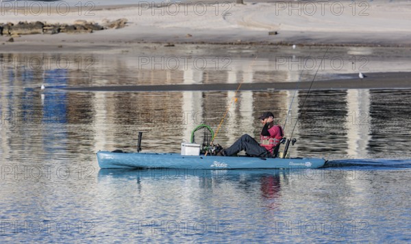 Man in Hobie kayak heads into the Gulf of Mexico for fishing at Gulfport, Mississippi, USA