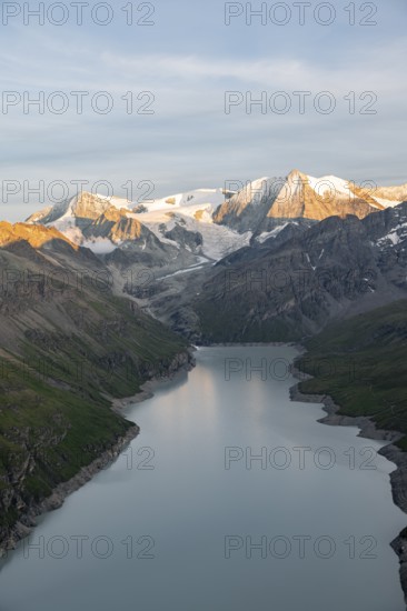 View at the summit of Mont de la Blana, alpenglow at sunset, view of a blue mountain lake, Lac des Dix reservoir, behind mountain peak Mont Blanc de Cheilon with glacier, Hérménence, Valais Alps, Valais, Switzerland