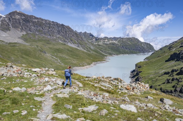 Mountaineer on a hiking trail in an idyllic mountain landscape, Lac des Dix reservoir in the background, Valais Alps, Valais, Switzerland