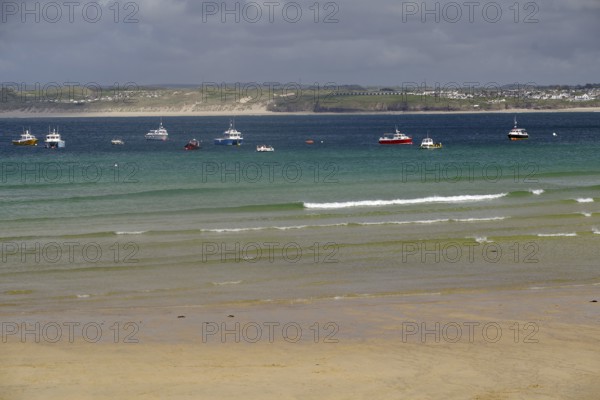 Several boats floating on a calm sea in front of a misty coastline, St Ives, Cornwall, England, United Kingdom