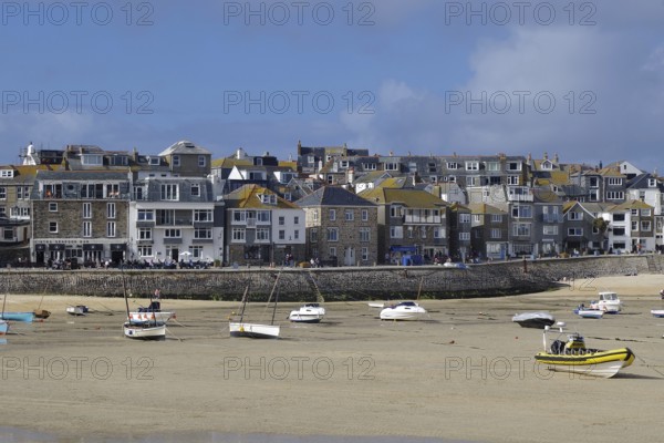 A busy coastal harbour with many boats and a town with densely built houses, St Ives, Cornwall, England, United Kingdom