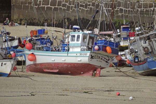 Fishing boats in the harbour on the dry dock, surrounded by a harbour wall and sandy bottom, St Ives, Cornwall, England, Great Britain