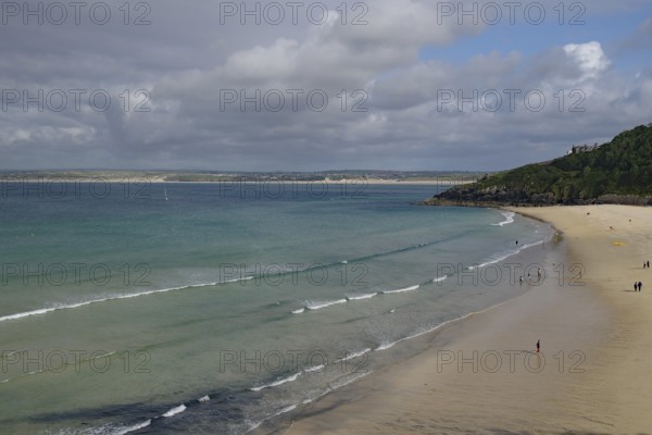 Spacious beach with gentle waves and few people under a cloudy sky, St Ives, Cornwall, England, United Kingdom