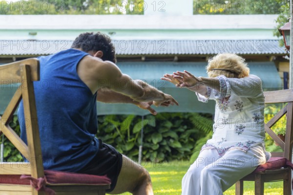 Physiotherapist assisting a senior woman with rehabilitation exercises in a vibrant home garden, enhancing health and mobility while promoting a healthy lifestyle outdoors