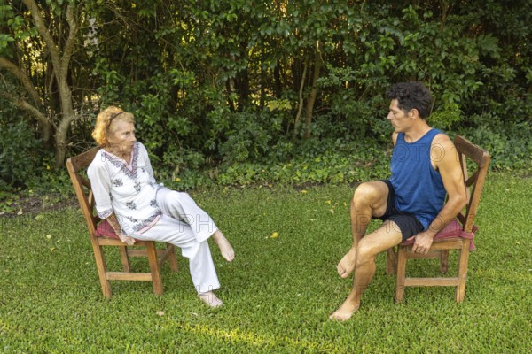 Physiotherapist guides a senior woman through gentle rehabilitation exercises, focusing on mobility and strength training in a peaceful outdoor setting