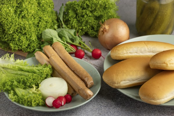 Various ingredients on plates, including salad, sausages and bread rolls
