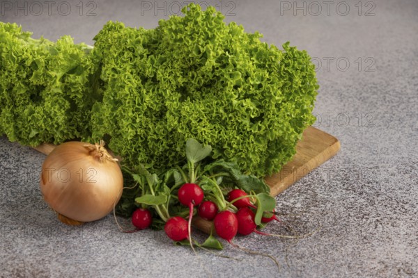 Green salad, onion and radish on a wooden board