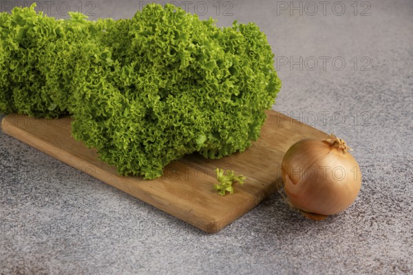 Green salad with an onion on a wooden board