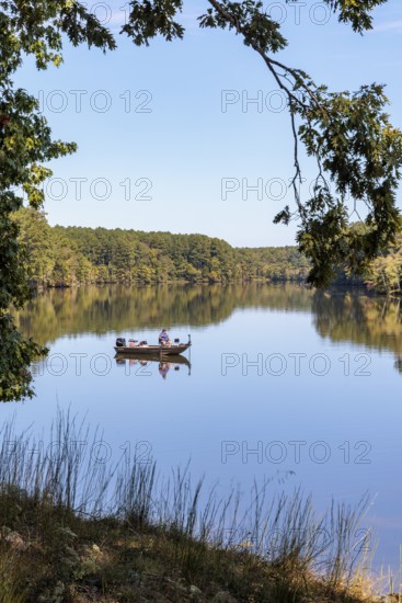 Man fishing in small boat on Pin Oak Lake in Natchez Trace State Park near Wildersville, Tennessee