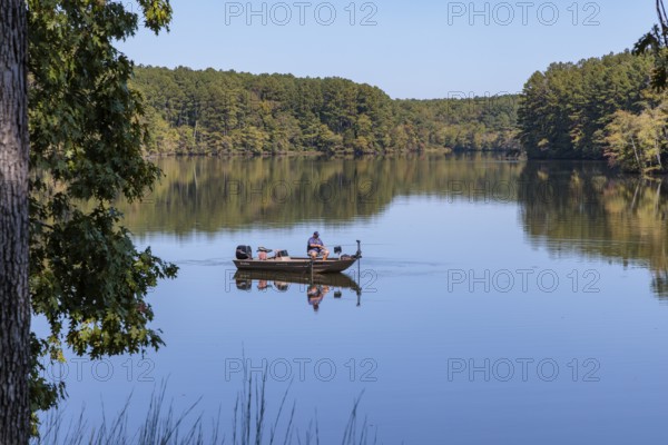 Man fishing in small boat on Pin Oak Lake in Natchez Trace State Park near Wildersville, Tennessee