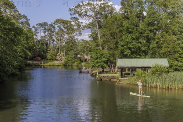 Young woman paddleboarding on the Magnolia River in Magnolia Springs, Alabama
