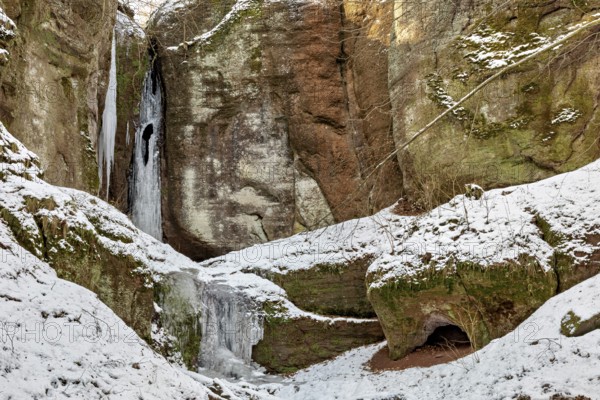Snow-covered rocks with icicles and a small cave in winter, the Dragon Gorge near Eisenach in Thuringia